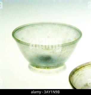 Un délicat bol translucide avec une forme lisse et arrondie et un éclat subtil, reposant sur une petite base circulaire. La surface affiche une texture marbrée douce, faisant allusion à son artisanat et matériaux., romain, plat, 4ème siècle après JC, verre, H. 1 1/8 - 1 1/4 x D. 6 3/8 po., Art classique avec une touche moderne réinventée par Artotop Banque D'Images