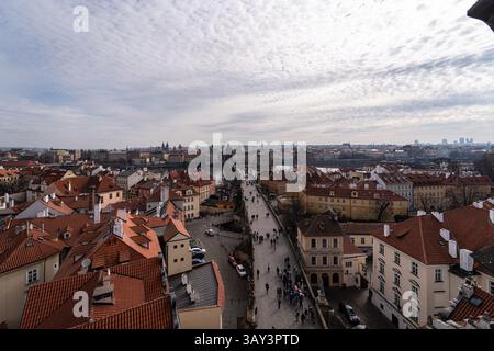 Magnifique photo aérienne de Prague montrant une rue bondée flanquée de toits en terre cuite traditionnels, avec l'architecture historique de la ville Banque D'Images