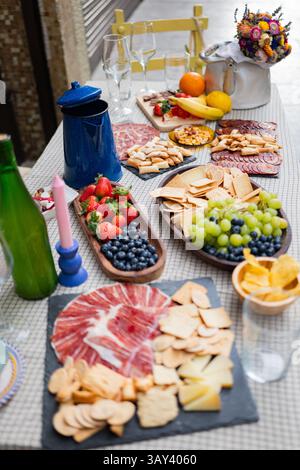 Une table extérieure accueillante avec collations variées, fruits et fromages. Les arrangements colorés comprennent des raisins, des baies et des craquelins, parfaits pour casu Banque D'Images