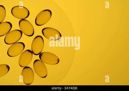 Une image frappante avec plusieurs gélules d'Oméga-3 et de vitamine d agencées habilement sur une surface jaune vif, mettant en évidence la santé et la nutrition. Banque D'Images