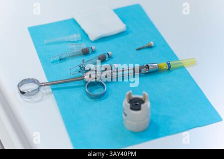 Seringue d'anesthésie dentaire et outils apparentés sur une surface stérile bleue. La configuration suggère la préparation pour le nettoyage des dents dans un environnement clinique. Banque D'Images