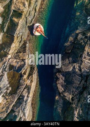 Vue de dessus d'une femme méconnaissable flottant sur un gonflable dans les eaux claires d'une piscine naturelle sur les côtes accidentées de Tindaya Beach, Fuerte Banque D'Images
