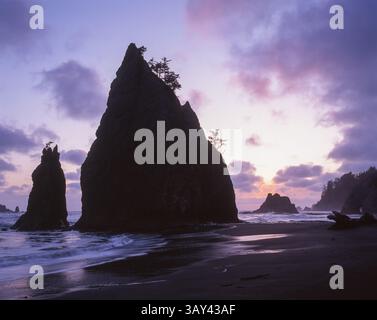 Scène côtière époustouflante avec de hautes couches de mer déchiquetées sur un ciel coloré au coucher du soleil, avec de douces vagues de l'océan qui rodent sur le shor accidenté Banque D'Images