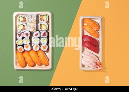 Plan minimaliste au plafond de boîtes à emporter à sushi sur un fond de couleur divisée, avec des rouleaux de nigiri et de maki avec un éclairage directionnel puissant Banque D'Images