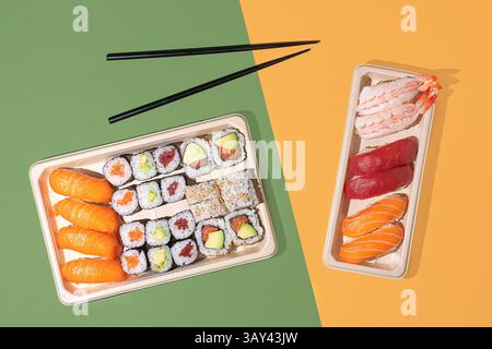 Plan minimaliste au plafond de boîtes à emporter à sushi sur un fond de couleur divisée, avec des rouleaux de nigiri et de maki avec un éclairage directionnel puissant Banque D'Images