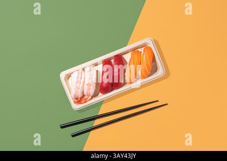 Plan minimaliste au-dessus de la boîte à emporter nigiri sur un fond de couleur divisée, avec un éclairage directionnel puissant. Parfait pour les thèmes japonais Banque D'Images