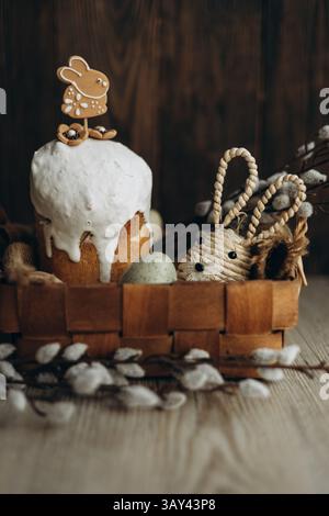 Une exposition captivante d'un Kulich traditionnel, recouvert de glaçage blanc, avec un biscuit au pain d'épice lapin de Pâques. Dans un panier en bois rustique à côté par exemple Banque D'Images