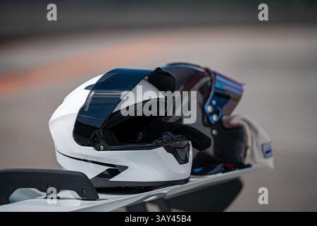 Vue rapprochée de deux casques de sport reposant sur une moto, soulignant l'importance de la sécurité et du style dans le sport automobile. Les casques sont modernes, Banque D'Images