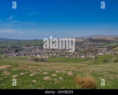 Vue panoramique sur Settle, une ville pittoresque dans les Yorkshire Dales, avec des collines verdoyantes, des maisons dispersées et un ciel bleu clair Banque D'Images
