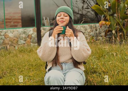 Une femme aime siroter une boisson chaude à l'extérieur, embrassant la tranquillité et la beauté naturelle autour d'elle Banque D'Images