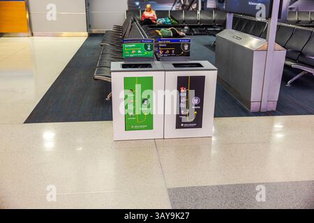 Poubelles de compost et de déchets avec panneaux de tri détaillés au terminal de l'aéroport JFK avec passagers se reposant en arrière-plan. New York. ÉTATS-UNIS. Banque D'Images