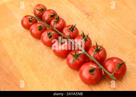 Tomates cerises rouges mûres sur la vigne, surface en bois, tomates bio, cuisine gourmande, tomates de vigne Banque D'Images