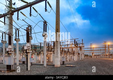 Sous-station électrique au Brésil, éclairée au crépuscule, avec son réseau de tours, transformateurs et lignes électriques contre la lumière du ciel. Banque D'Images