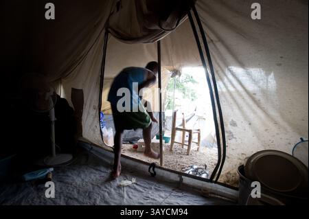 28 juin 2010 - Port au Prince, Haïti - Peterson, 12 ans, sort de la porte de la tente familiale dans un camp de déplacés dans le quartier de Delmas à Port au Prince six mois après le tremblement de terre haïtien. (Crédit image : © Jessica Brandi Lifland/ZUMApress.com) Banque D'Images