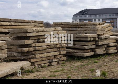 Piles de vieilles dalles de béton altérées sur le chantier de construction avec bâtiment résidentiel moderne en arrière-plan. Aménagement urbain, recyclage des matériaux Banque D'Images
