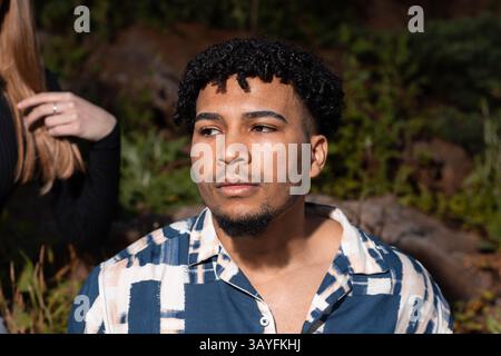 Gros plan Portrait d'un jeune homme élégant aux cheveux bouclés dans un cadre naturel en extérieur Banque D'Images
