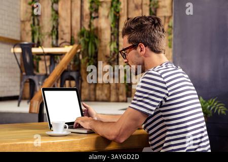 Homme travaillant sur ordinateur portable avec écran blanc à la table de café rustique tout en sirotant du café, espace de copie Banque D'Images