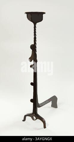 Ce chandelier en fer haut et élancé présente un motif torsadé et une base dotée de trois pieds de maintien et d'un porte-bougie peu profond en haut. Andiron (Landiers en Hastiers), français, début du XVIe siècle, fer, fabriqué en France au XVIe siècle, ces deux objets en fer forgé à la main, appelés andirons, servaient à supporter des bûches de bois à l'intérieur des cheminées de cuisine domestiques. Tous les andirons n'étaient pas aussi élaborés que ceux-ci : il y a des crochets décorés de coquilles pour soutenir des broches de fer pour rôtir de grandes viandes avec des cintres en forme de coeur et des tasses en forme de panier qui pourraient contenir des ustensiles, des pots, et Banque D'Images