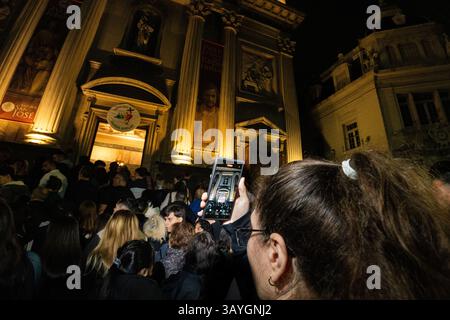 Une jeune femme filme la messe sur son téléphone portable depuis les marches. À la basilique de San José, dans le quartier de Flores, où Jorge Bergoglio a grandi et a fait ses premiers pas dans la prêtrise, l’archevêque de Buenos Aires, Jorge García Cuerva, a dirigé une messe émotionnelle en hommage au pape François. Il a dit : « nous avons perdu le Pape des pauvres, des marginalisés, de ceux que personne ne veut, de ceux qui sont si nombreux à exclure. » L'église débordait de gens. La vice-présidente Victoria Villarruel était présente. Banque D'Images
