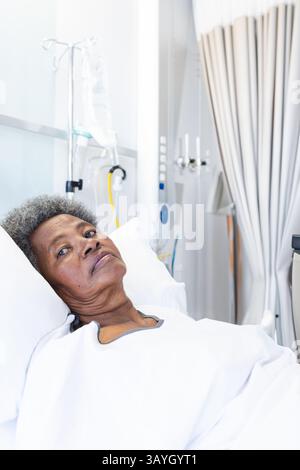 Femme afro-américaine senior couchée dans une chambre d'hôpital sur le lit, avec perfusion et perfusion IV Banque D'Images