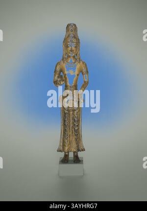 Une statue magnifiquement conçue d'une divinité, ornée de détails complexes et d'une expression sereine. La figure se tient élégamment avec une main tenant un objet, drapé dans une tenue fluide qui met en valeur des motifs élaborés, sur un fond légèrement éclairé qui rehausse sa teinte dorée. Guanyin (Avalokiteshvara), Royaume de Dali (v. 937–1253), XIIe siècle, Chine, cuivre doré, 34 × 6,4 × 5,6 cm (13 3/8 × 2 1/2 × 2 1/4 po.) Art classique avec une touche moderne réinventé par Artotop Banque D'Images