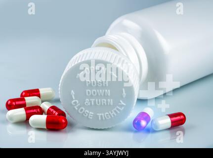 Pilules rouges et blanches à côté d'une bouteille en plastique avec un bouchon à l'épreuve des enfants. Médicaments sur ordonnance, sécurité des emballages et contrôle des soins de santé. Pharmacie Banque D'Images