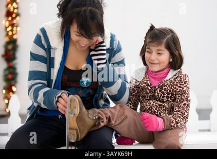 04 janvier 2010 - Sacramento, USA - la garde de skate Jessica Williams, à gauche, resserre les skates de Mariann (cq - no ''e'') Mendez lors d'une sortie sur la patinoire de Midtown lundi 4 janvier 2010. La patinoire a déménagé à l’emplacement de la 20e Rue cette année après que la construction de la route a fermé l’ancien spot du centre-ville, le plaçant maintenant au cœur des activités mensuelles du deuxième samedi. Ce samedi, les organisateurs présenteront un spectacle de patinage artistique chorégraphié pendant la populaire promenade artistique en plein air. La patinoire peut accueillir plus de 200 patineurs à tout moment et a attiré une vingtaine de milliers de personnes depuis son ouverture à proximité Banque D'Images