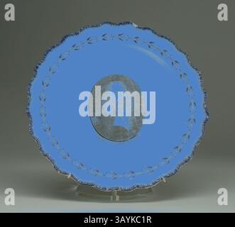 Une assiette décorative représentant un portrait central encadré par une délicate couronne de feuilles de laurier, sur fond bleu vif. Plate, c. 1790, anglais pour le marché américain, Leeds, Angleterre, Creamware, Diam. 24,3 cm (9 9/16 po) Art classique avec une touche moderne réinventé par Artotop Banque D'Images