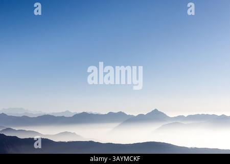 Beau fond de chaîne de montagnes avec ciel bleu et brume blanche dans le soleil tôt le matin. Grand espace de copie en haut pour votre texte. Banque D'Images
