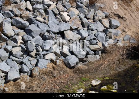 pile grise de rochers le long de l'eau Banque D'Images