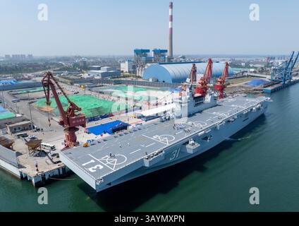 Chengmai, Chine.22 avril 2025. Vue aérienne du navire d'assaut amphibie Hainan amarré au port de Macun le 22 avril 2025 dans le comté de Chengmai, province chinoise de Hainan. Des navires de guerre, y compris un navire d'assaut amphibie de type 075, en préparation d'événements portes ouvertes pour célébrer le prochain anniversaire de fondation de la marine de l'Armée populaire de libération de la Chine (APL), ont commencé à arriver dans les villes côtières chinoises lundi. Crédit : Luo Yunfei/China News Service/Alamy Live News Banque D'Images