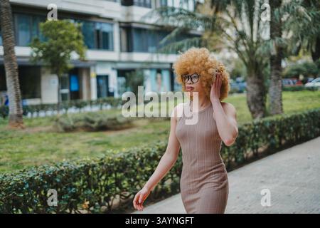 Femme élégante avec cheveux afro marchant dans un parc de la ville Banque D'Images