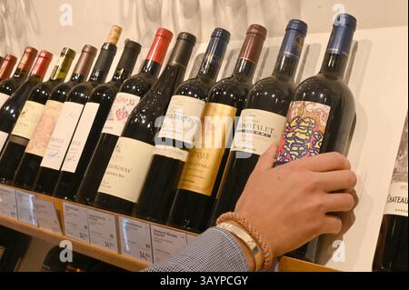 Hambourg, Allemagne. 23 avril 2025. Un employé vient chercher une bouteille de vin dans une succursale de 'Jacques' Wein-Depot' dans le quartier Osdorf de Hambourg. Jacques' Wein-Depot Wein-Einzelhandel GmbH' est une filiale de 'Hawesko Holding se', qui publie son rapport annuel. Crédit : David Hammersen/dpa/Alamy Live News Banque D'Images