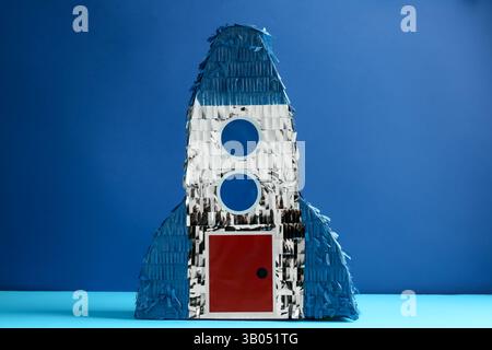 Pinata lumineux en forme de vaisseau spatial sur fond bleu Banque D'Images