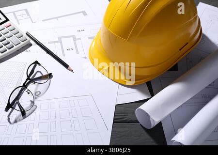 Différents dessins architecturaux, verres, crayon et calculatrice sur table en bois gris, gros plan Banque D'Images