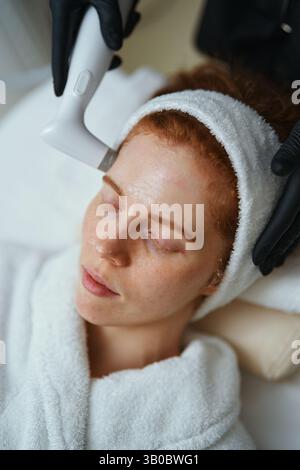 Femme recevant un traitement de soin de la peau dans un cadre de spa serein Banque D'Images