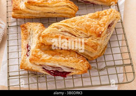Pâtisseries feuilletées avec de la confiture de cerises ou de baies sur une plaque à pâtisserie fraîchement cuite et prête à manger Banque D'Images