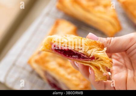 Pâtisseries feuilletées avec de la confiture de cerises ou de baies sur une plaque à pâtisserie fraîchement cuite coupée en deux pour montrer la garniture Banque D'Images