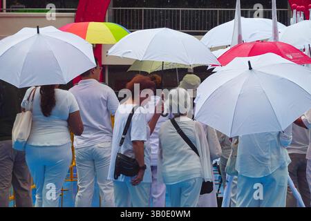 Singapour 2025 avril 23 - les partisans du PAP se tiennent sous la pluie sous des parapluies à l'école de Chongfu le jour de la nomination lors de l'élection générale de Singapour, showi Banque D'Images