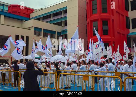 Singapour 2025 avr 23 - les partisans du PAP se sont vêtus de drapeaux du parti en vague blanche devant l'école de Chongfu le jour de la nomination lors des élections générales de Singapour Banque D'Images