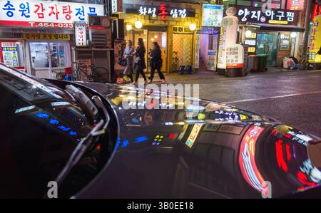 Busan, Corée du Sud - 19 mars 2018 : les rues éclairées la nuit présentent un paysage urbain vibrant avec des devantures illuminées et des reflets colorés Banque D'Images