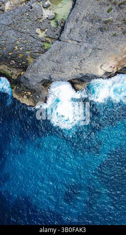 Superbe vue aérienne des falaises côtières spectaculaires rencontrant des vagues turquoises vibrantes, capturant la beauté brute et les textures puissantes du rivage de l'océan Banque D'Images