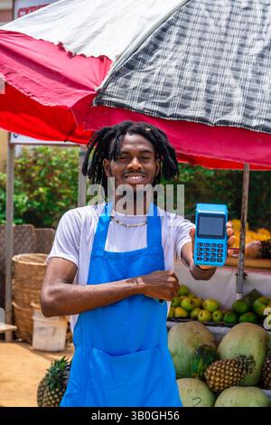 Homme d'affaires noir africain excité utilisant le paiement NFC, en utilisant la machine de point de vente Banque D'Images