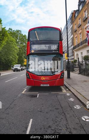 Londres, Angleterre, 11 juillet 2023, le bus à impériale rouge n° 188 en direction de North Greenwich s'arrête sur une rue calme encadrée par des arbres et un mélange de and moderne Banque D'Images
