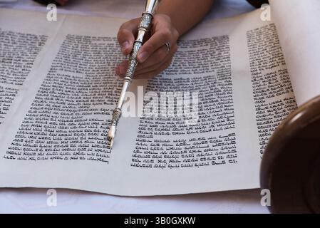 Gros plan d'une main tenant un yad ou un pointeur pour guider le lecteur de Torah à travers le texte hébreu. Banque D'Images