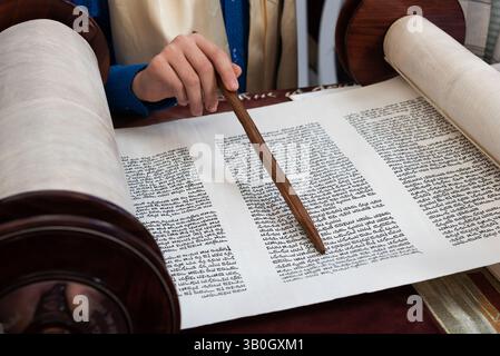 Gros plan d'une main tenant un yad ou un pointeur pour guider le lecteur de Torah à travers le texte hébreu. Banque D'Images