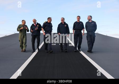 (Gauche-droite) Capitaine Colin McGannity (RN) commandant du groupe aérien de transport, le secrétaire à la Défense John Healey, le commodore James Blackmore commandant du groupe d'attaque de porte-avions, le premier ministre Sir Keir Starmer, le vice-amiral Andy Burns commandant de la flotte et le capitaine Will Blackett capitaine du HMS Prince of Wales marchent sur la rampe de décollage du HMS Prince of Wales, le porte-navire phare de la Royal Navy, à Plymouth, dans le Devon, avant un déploiement de huit mois dans la région Indo-Pacific HighMast. Le navire, qui a quitté Portsmouth mardi, se rendra en Méditerranée, Middle E. Banque D'Images