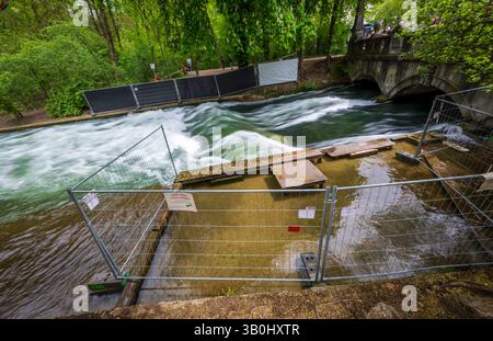 Munich, Allemagne. 24 avril 2025. Des barres avec des panneaux d'avertissement ferment la vague artificielle sur l'Eisbach. Un surfeur qui est tombé sur la vague d'Eisbach dans le jardin anglais il y a une semaine est mort à l'hôpital. Crédit : Peter Kneffel/dpa/Alamy Live News Banque D'Images