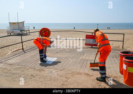 Exmouth, Devon, Royaume-Uni. 24 avril 2025. Météo britannique : un employé du conseil sur le front de mer peignant de nouveaux panneaux no dogs à l'entrée de la plage de la station balnéaire d'Exmouth dans le Devon lors d'une chaude journée ensoleillée avant l'interdiction des chiens du 1er mai au 30 septembre. Crédit photo : Graham Hunt/Alamy Live News Banque D'Images