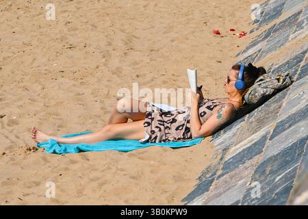 Exmouth, Devon, Royaume-Uni. 24 avril 2025. Météo britannique : un solarium sur la plage profitant du soleil chaud à la station balnéaire d'Exmouth dans le Devon. Crédit photo : Graham Hunt/Alamy Live News Banque D'Images